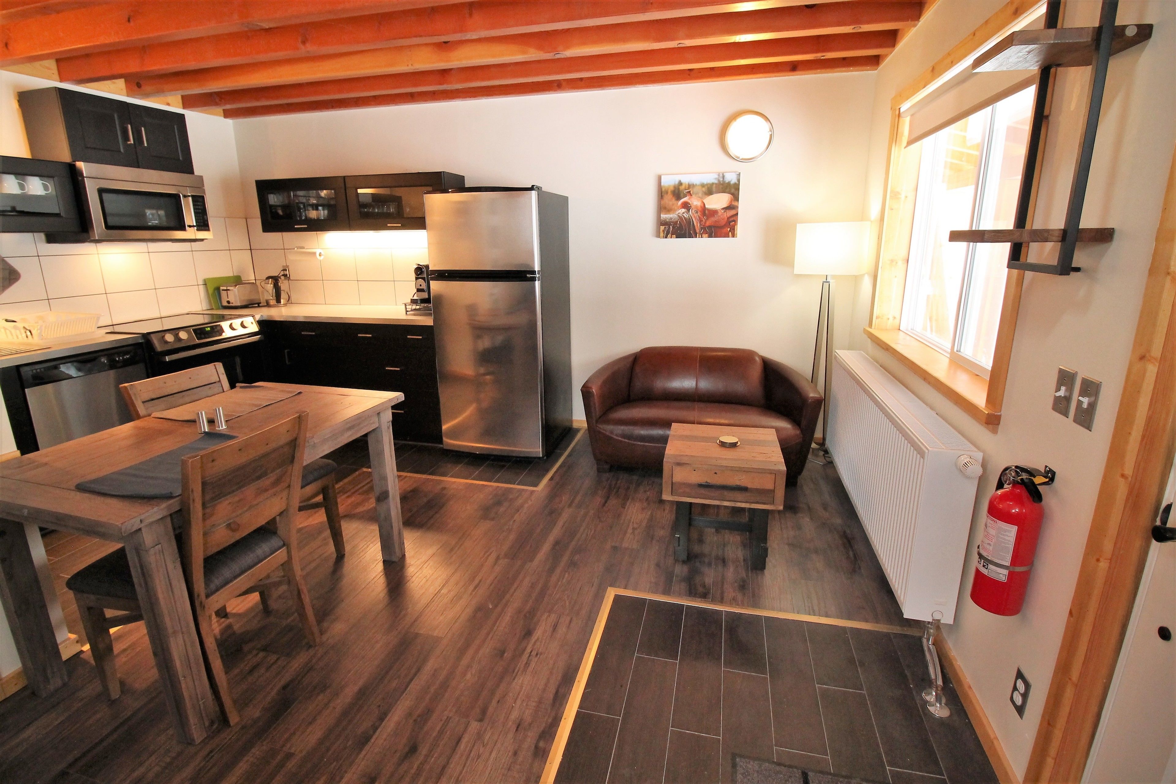 A compact kitchen with modern appliances, a dining table, and a cozy seating area.