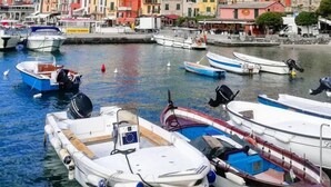 A marina with boats docked, colorful buildings, and a historic tower in the background. - L'Approdo Dell' Ammiraglio (La Spezia)