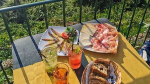 A table with food and drinks on a balcony overlooking a coastal town. - L'Approdo Dell' Ammiraglio (La Spezia)