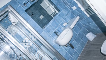 A bathroom with a blue tiled floor, a white sink, and a glass shower enclosure.