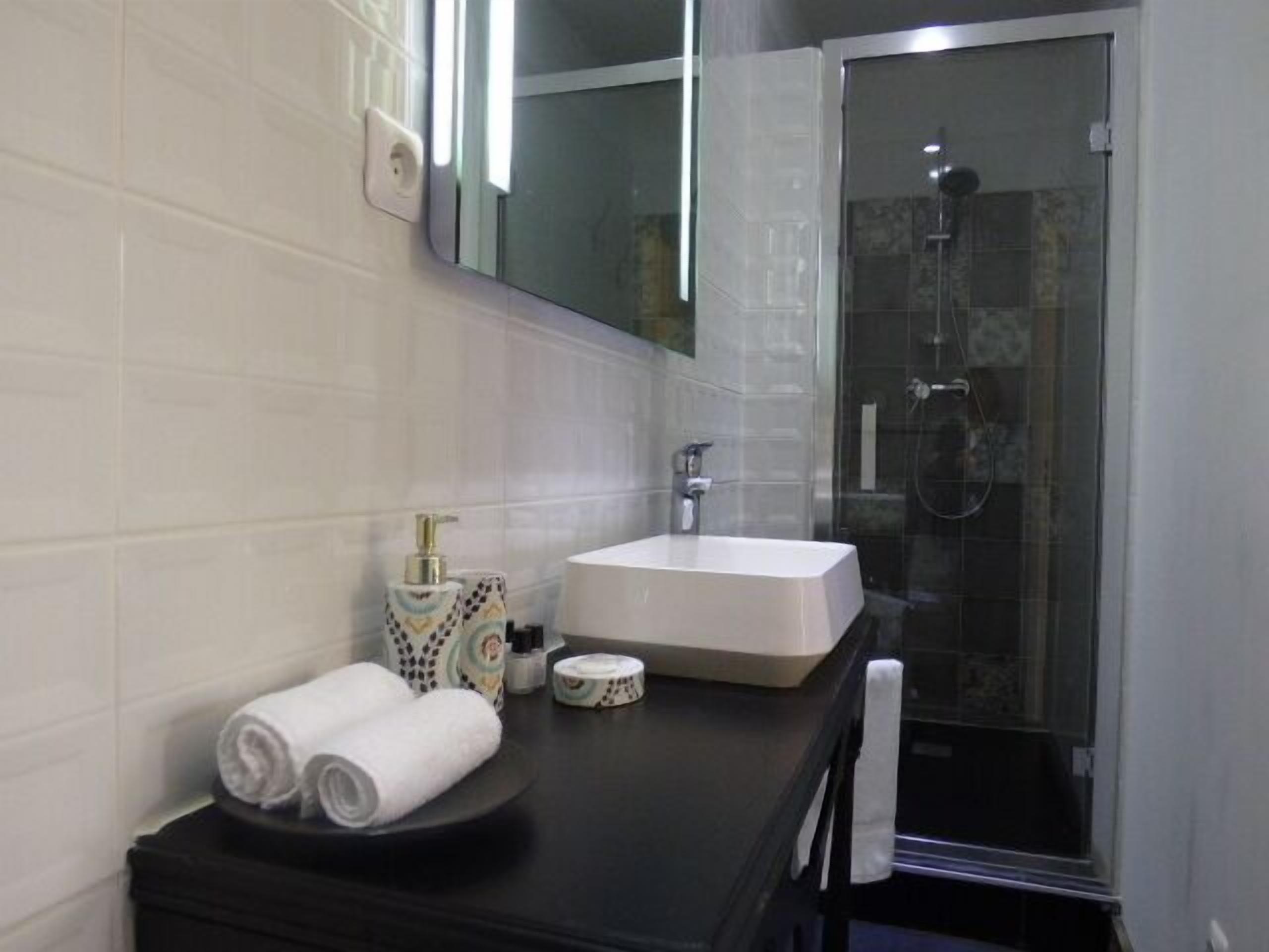 A modern bathroom with a white sink, a mirror, and a glass shower enclosure.