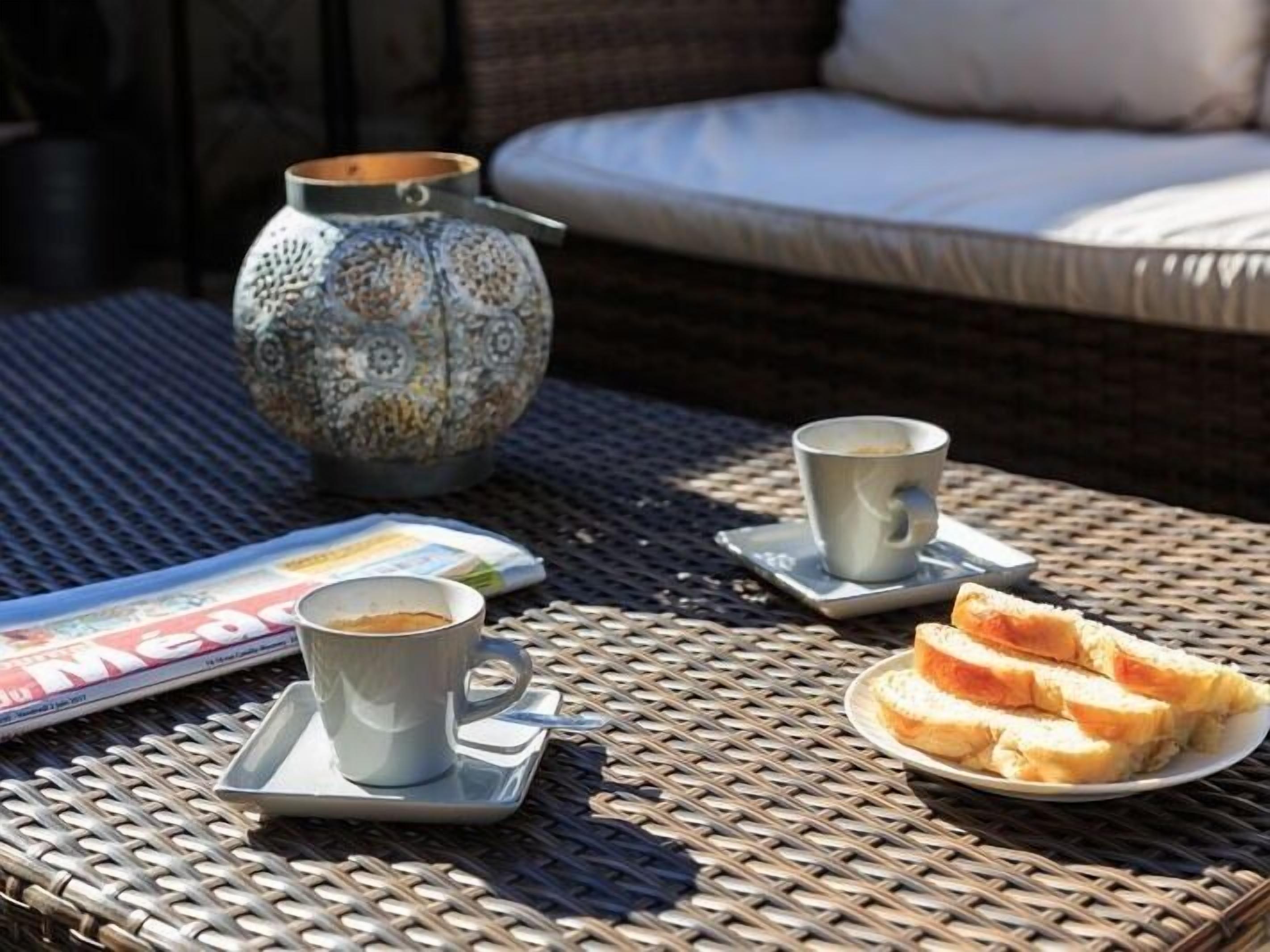 Ein Korbtisch mit einer Zeitschrift, einer Kaffeetasse, Toast und einer dekorativen Vase.