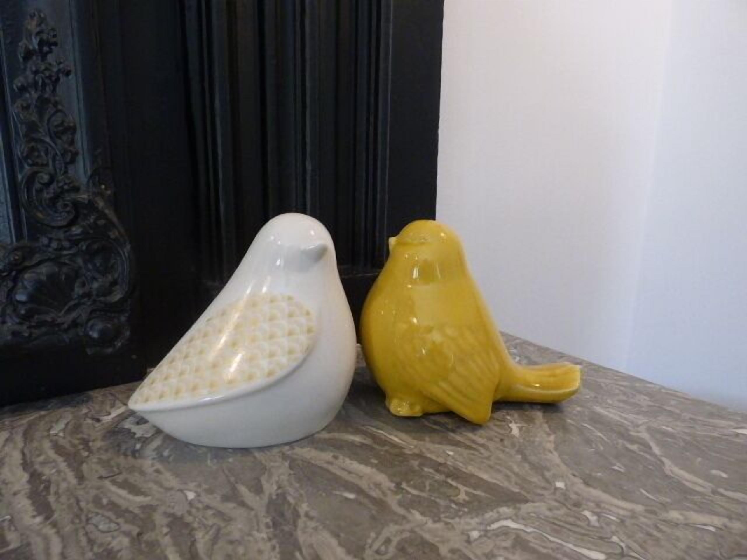 Two ceramic bird-shaped vases on a marble surface.