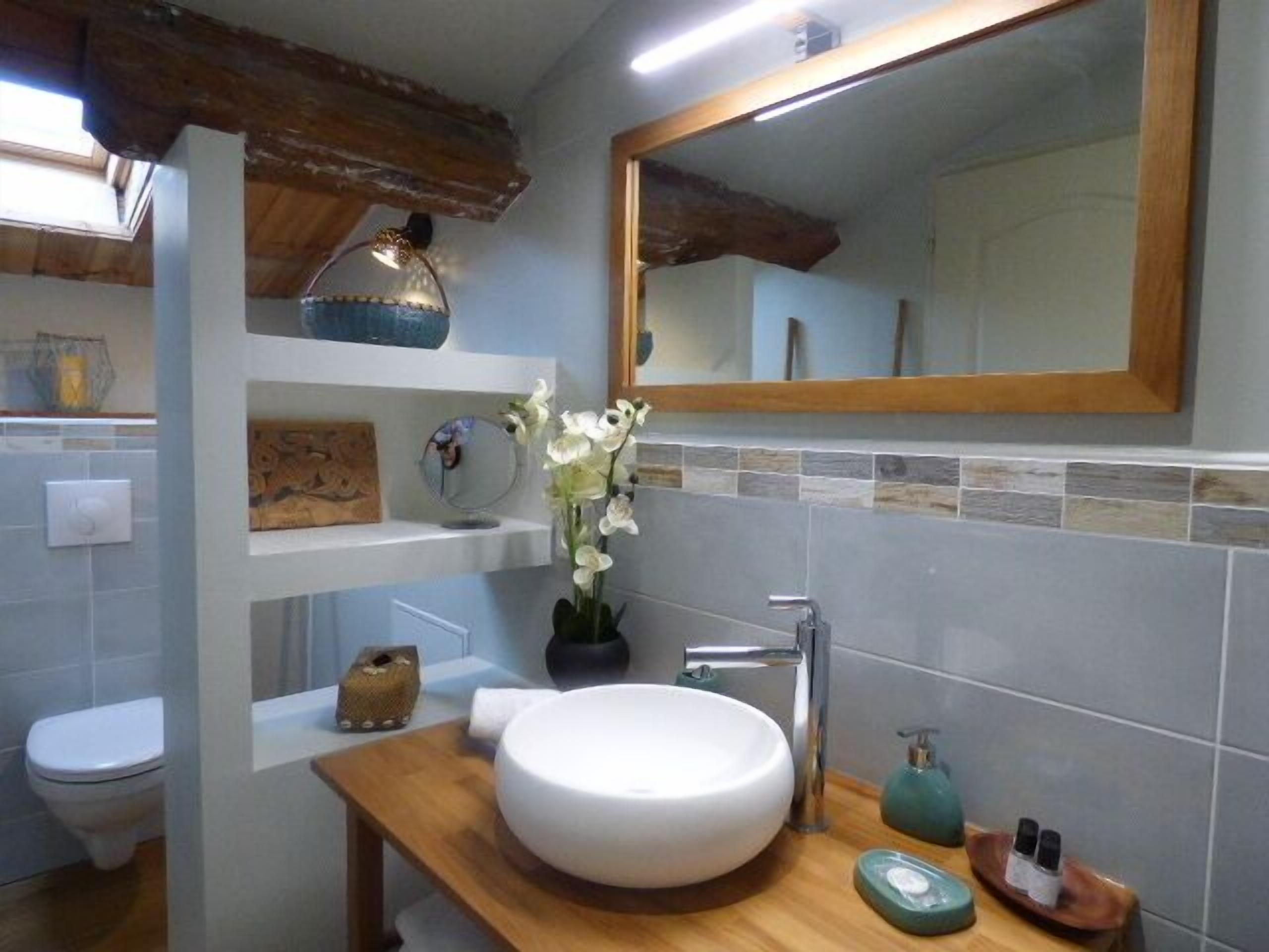 A bathroom with a white sink, a mirror, and a wooden vanity.