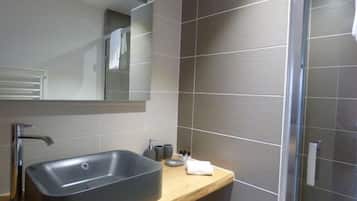 A modern bathroom with a large rectangular sink, a mirror above it, and a shower area with a glass door.