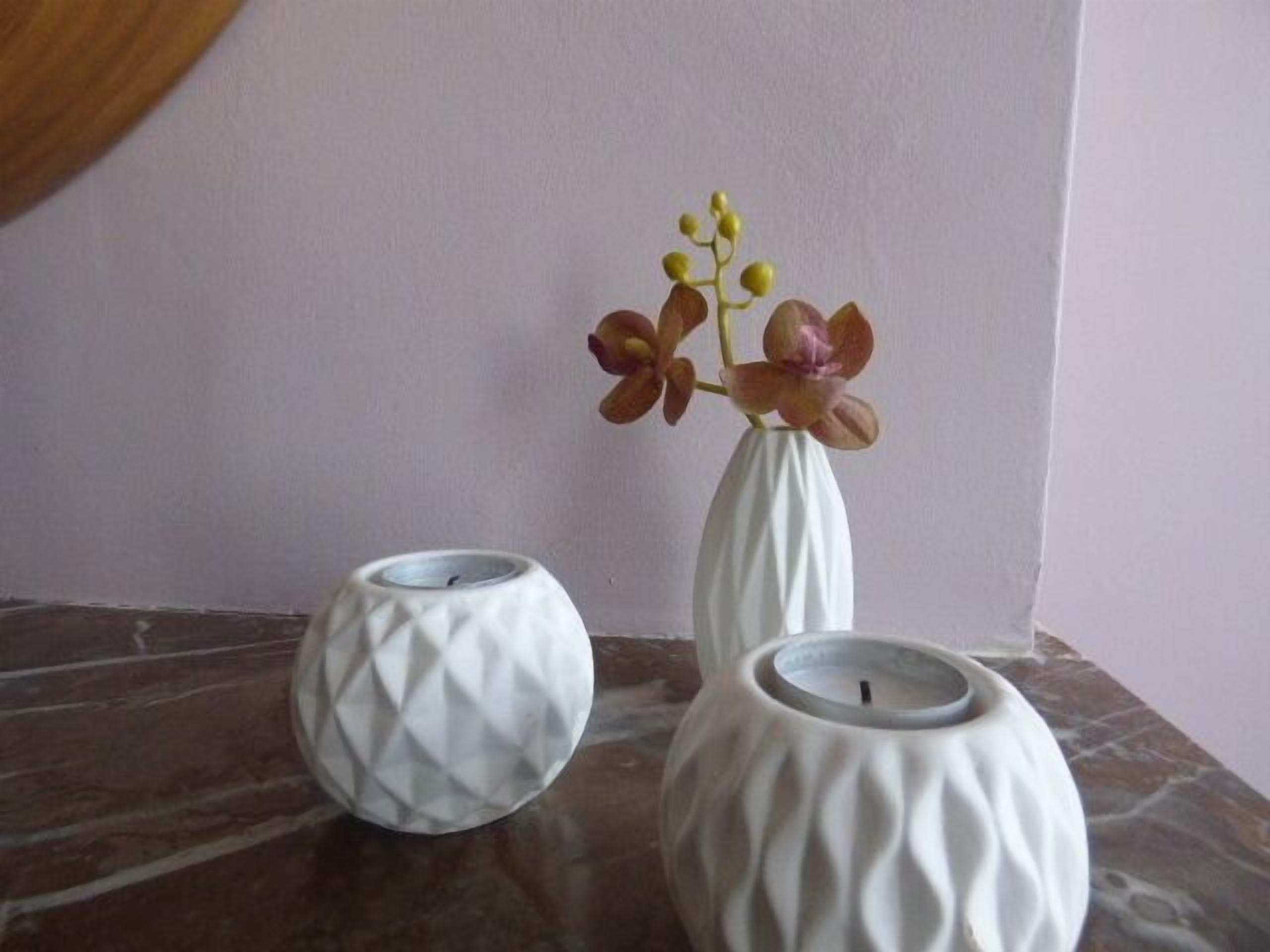 Three white vases with different textures on a stone surface.