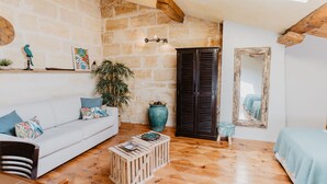 A cozy living room with a white sofa, wooden coffee table, and a large vase. There's a dark wooden cabinet and a mirror on the wall. - Le Coeur des Vignes (Pauillac)