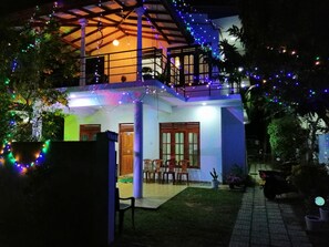 A two-story house with a balcony, string lights, and a small garden area. - Villa ok (Unawatuna)