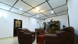 A room with a tiled floor, a brown leather sofa set, a wooden coffee table, and a cabinet with glass doors. - Villa ok (Unawatuna)