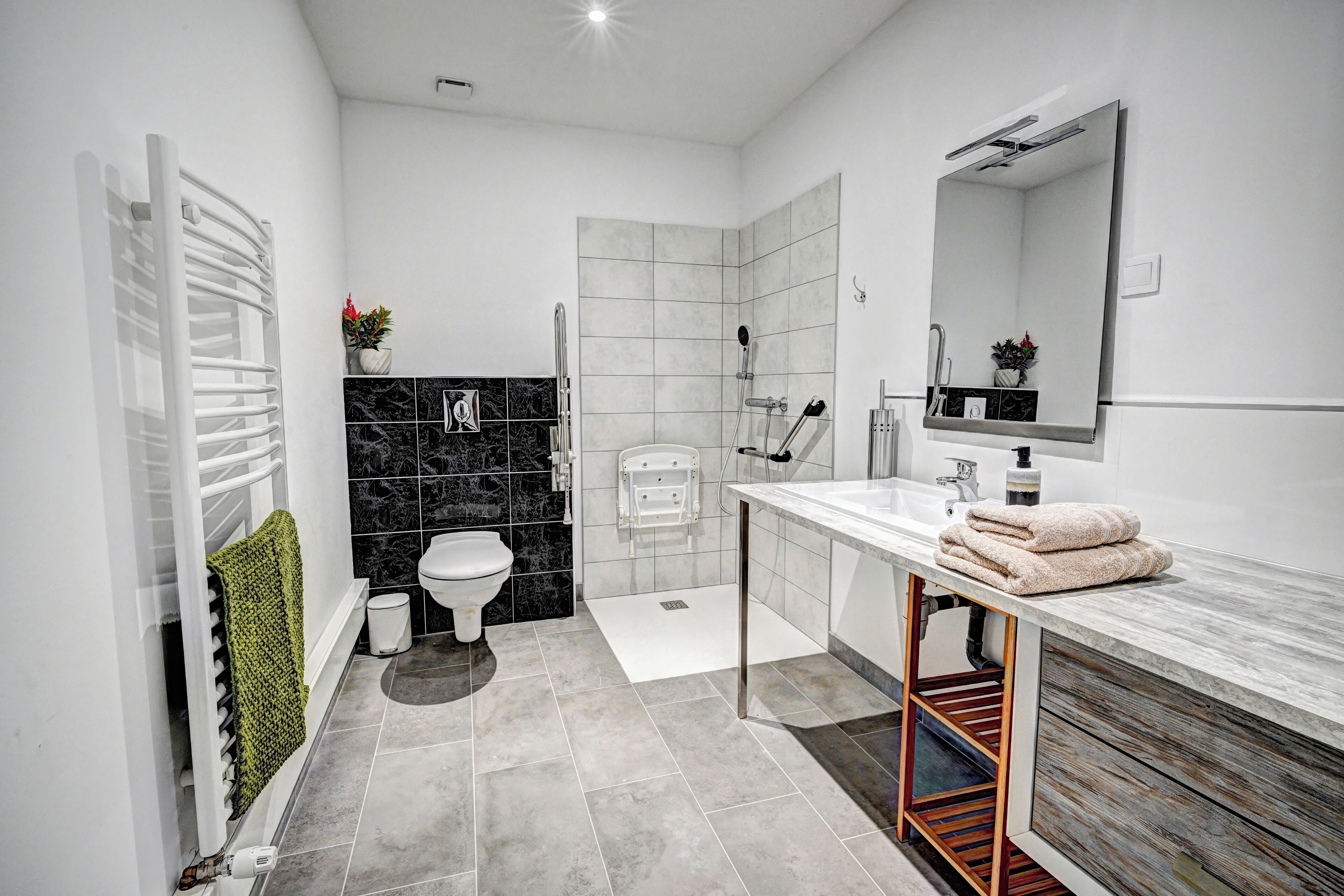Un baño moderno con un lavamanos blanco, un espejo grande, una ducha y un inodoro.