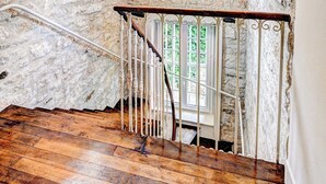 Una escalera con barandilla de madera y balaustradas blancas, que conduce a un rellano con una araña.