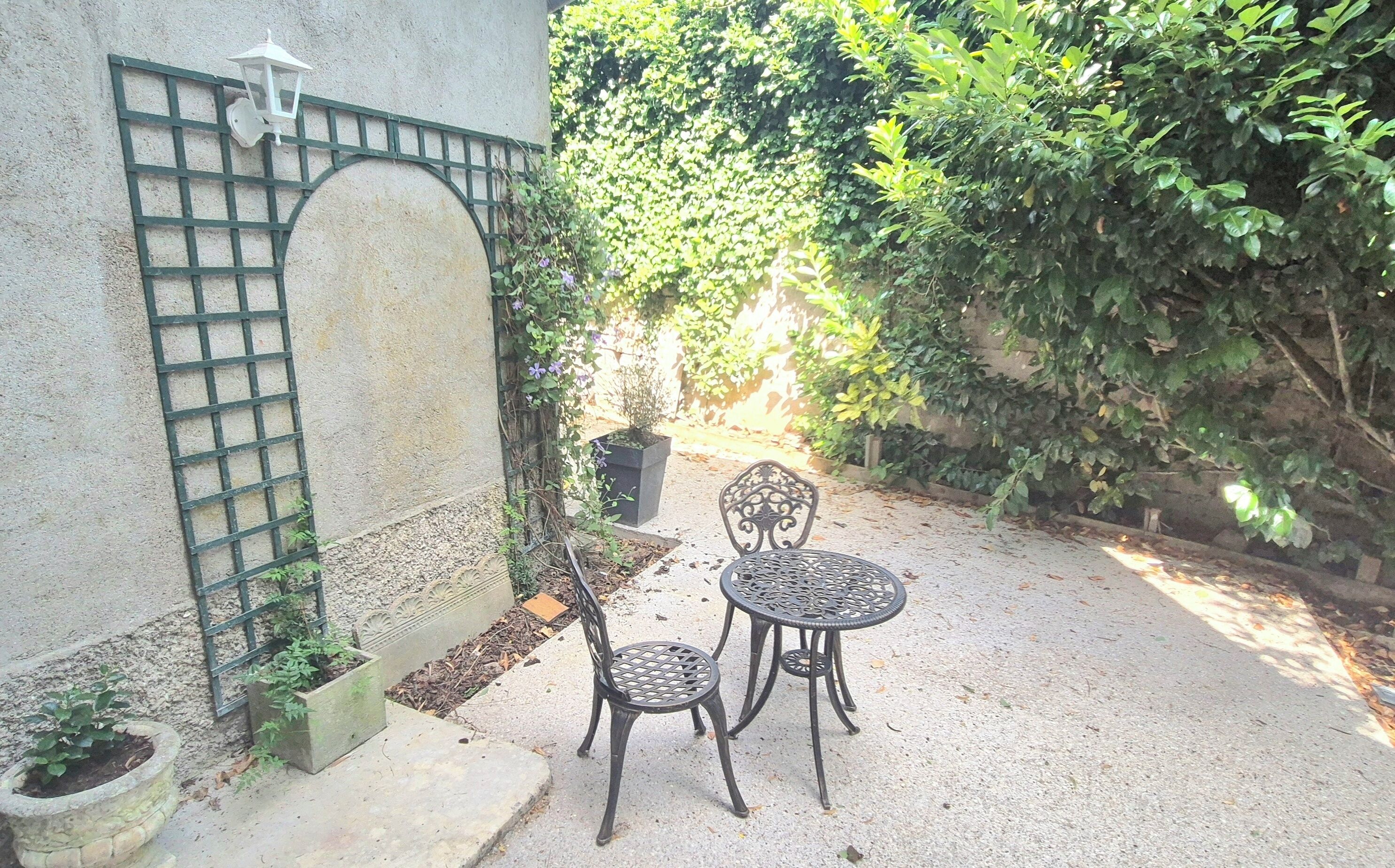 A courtyard with a metal gate, two chairs, and a small table.