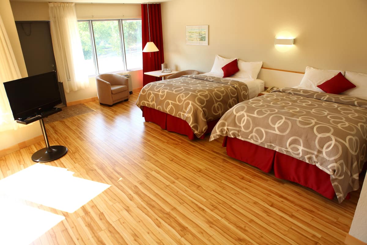 A hotel room with two beds, a TV, a desk, and a chair.