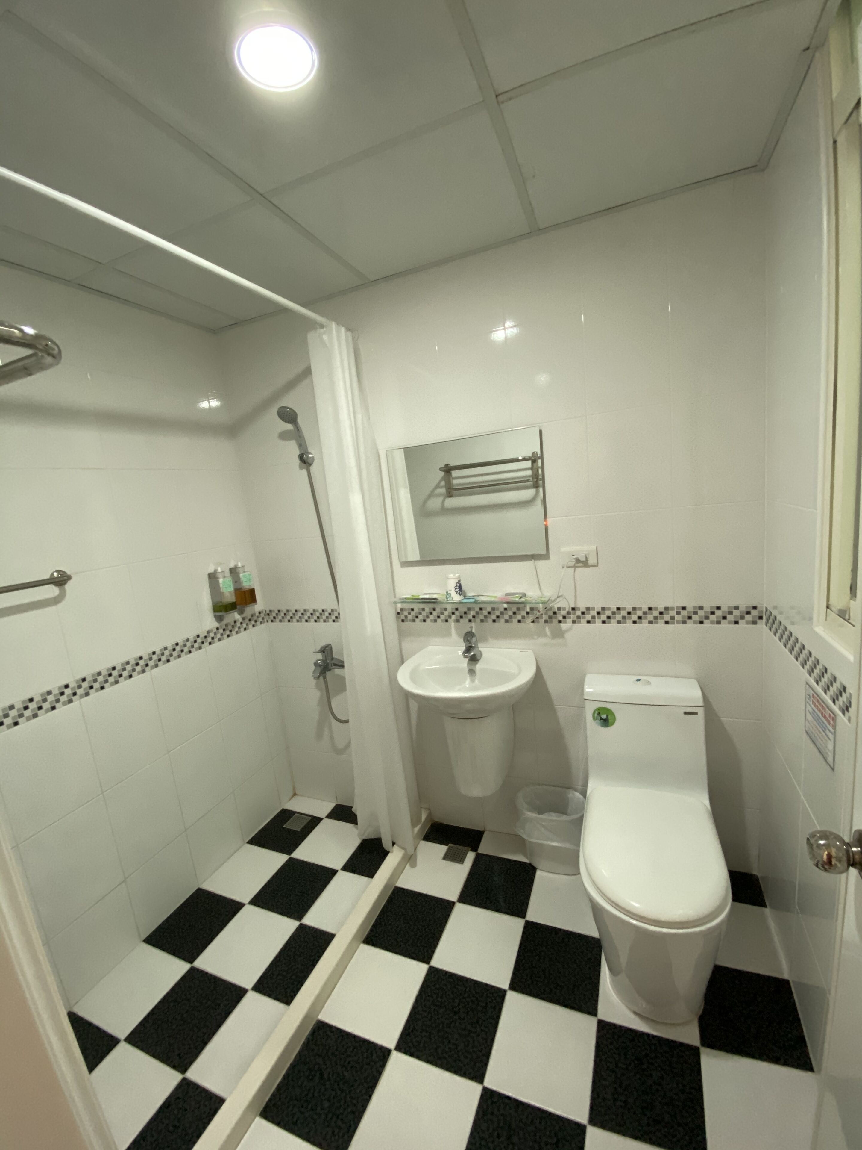 A bathroom with a black and white checkered floor, a white sink, and a toilet.