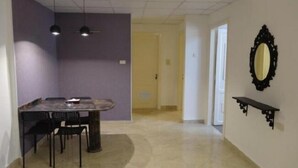 A dining area with a table and chairs, a ceiling fan, and a wall-mounted mirror. - Golden Palace Hotel Apartments (Amman)