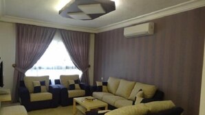 A living room with a sofa set, a coffee table, and a TV. - Golden Palace Hotel Apartments (Amman)