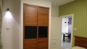 A bedroom with a wooden wardrobe, a bed, and a green-striped wall. - Golden Palace Hotel Apartments (Amman)