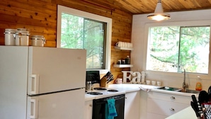 A compact kitchen with a refrigerator, stove, oven, and a window providing natural light. - Quaint, Clean & Updated Cottage- Steps From The Beach. (Port Franks)