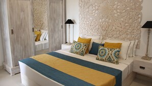 A bedroom with a large bed, two bedside tables, a wardrobe, and an ornate wall panel.
