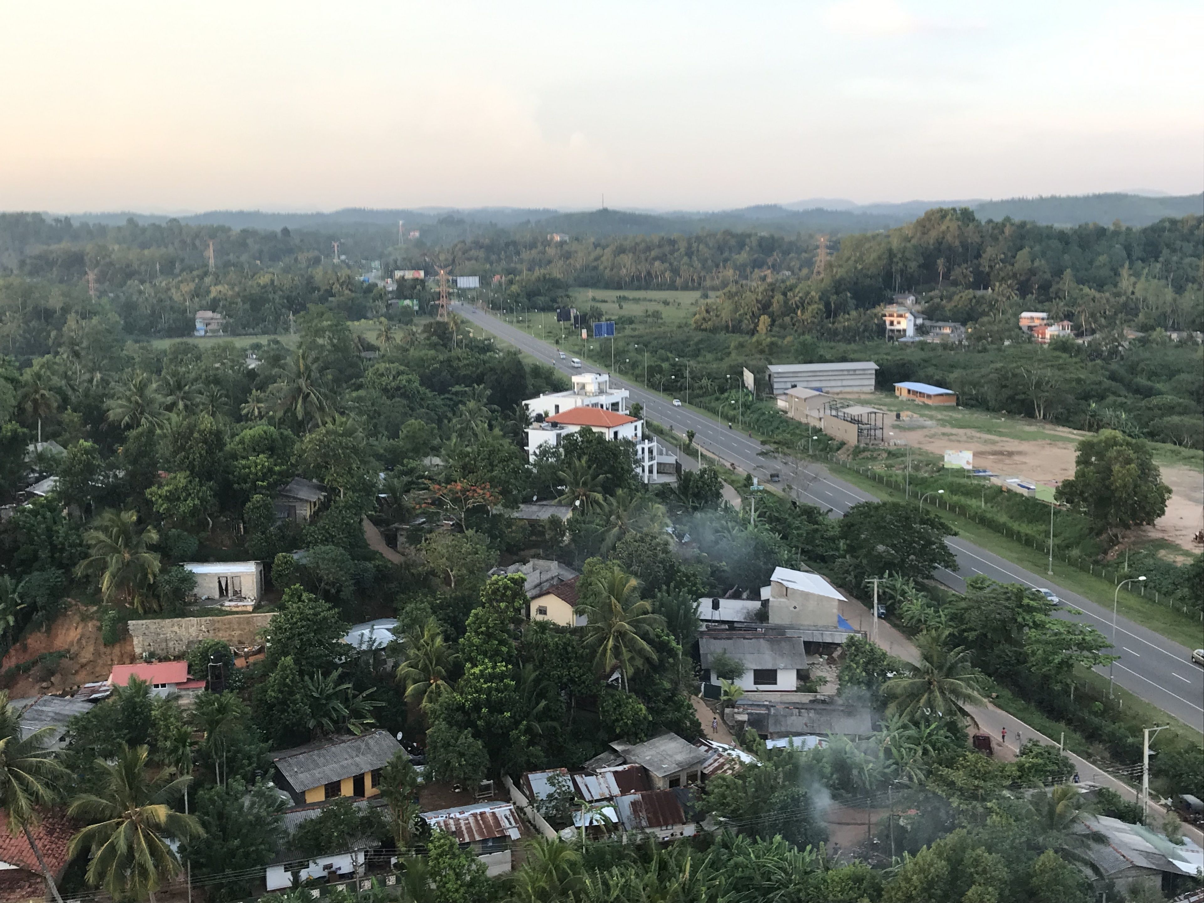 Une zone rurale avec une route, des maisons et de la végétation.