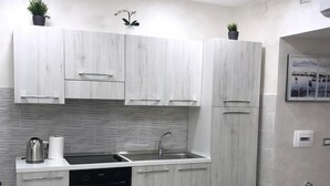 Una cocina moderna con armarios blancos, horno empotrado, lavamanos y comedor con mesa y sillas.