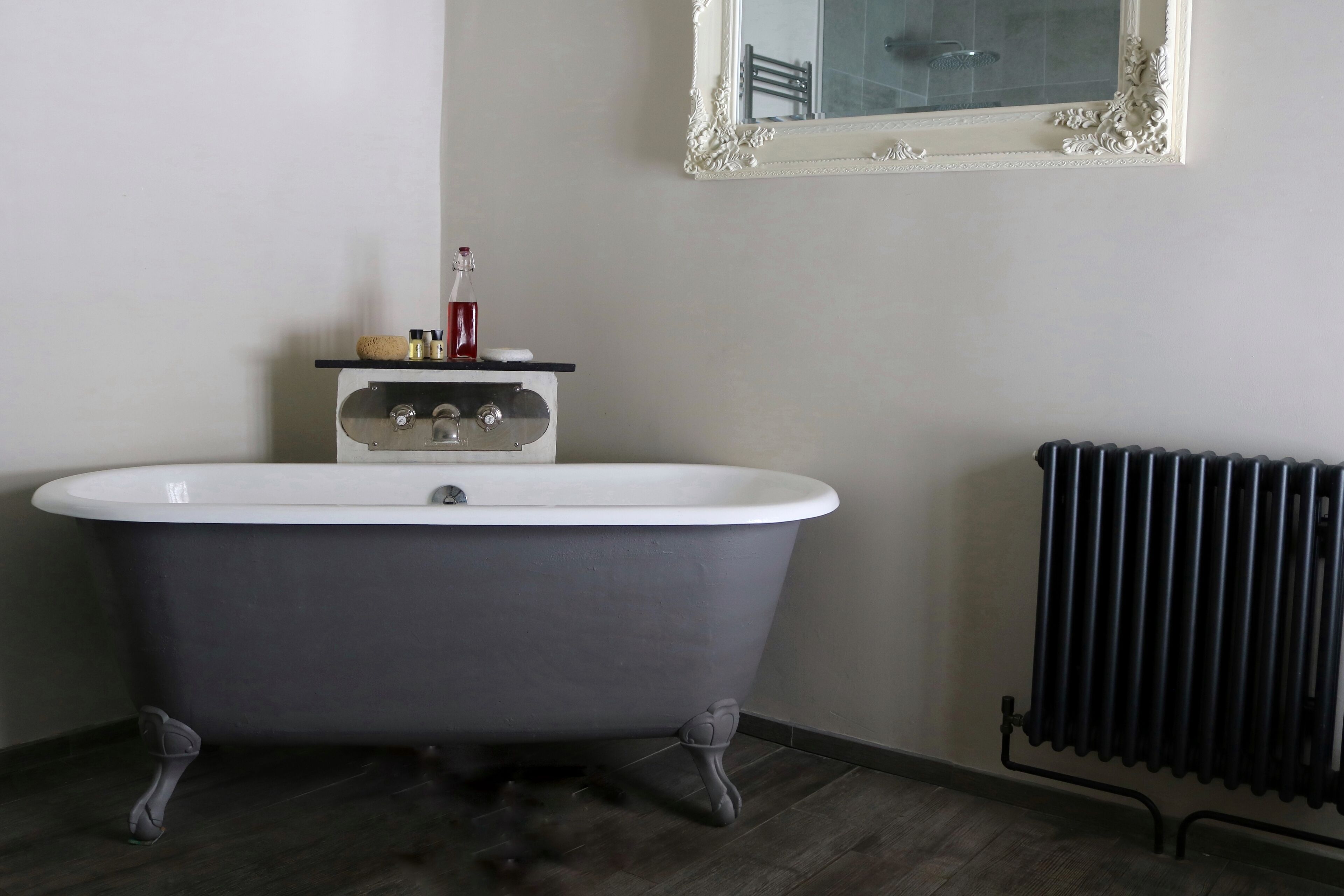 Een badkamer met een vrijstaand bad, een spiegel en een radiator.