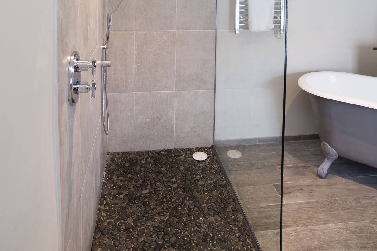 A modern bathroom with a glass shower enclosure, a freestanding bathtub, and a towel rack.