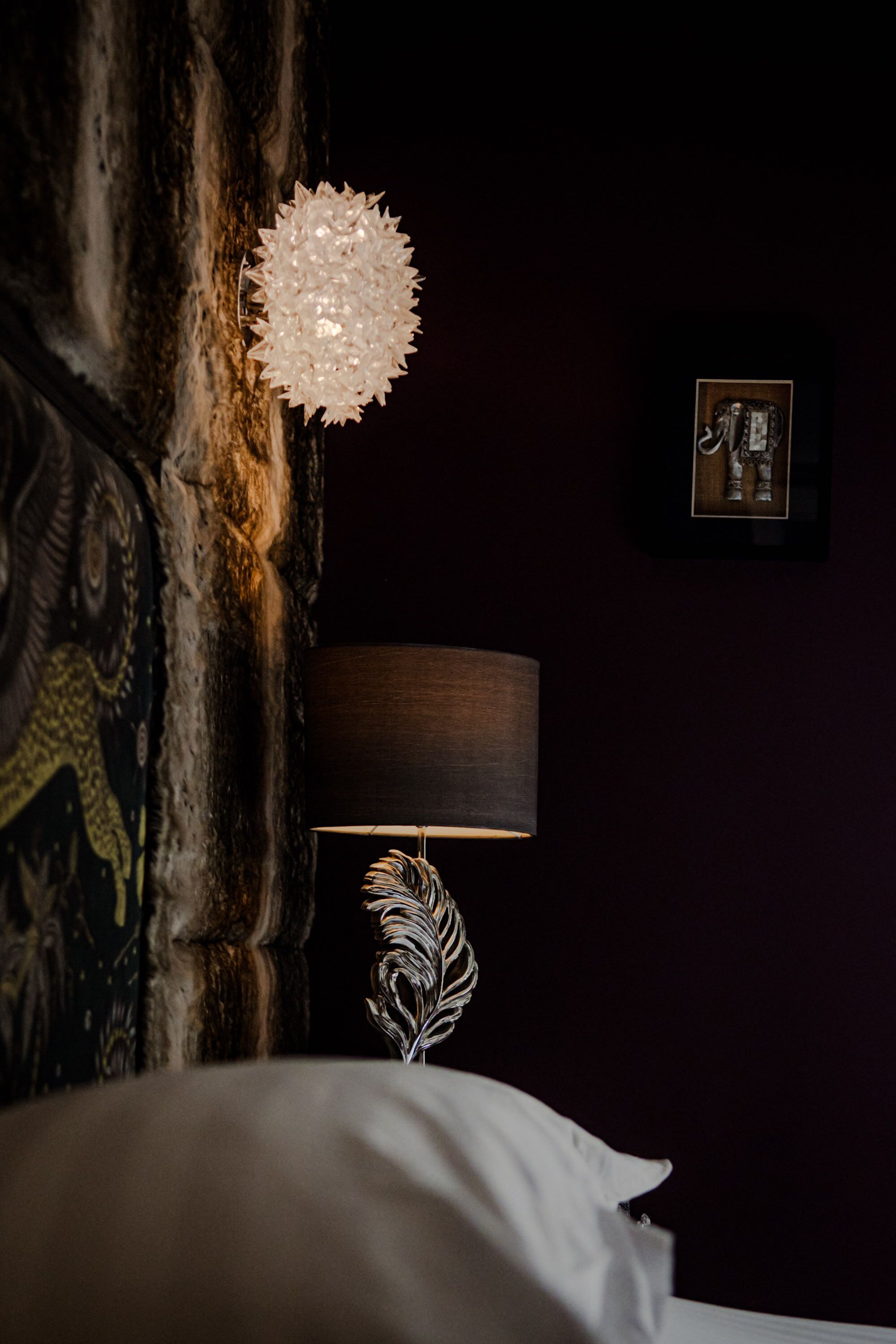 A bed with a decorative lamp and a feather-like ornament.