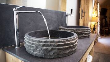 A modern bathroom with two stone sinks and a chrome faucet.
