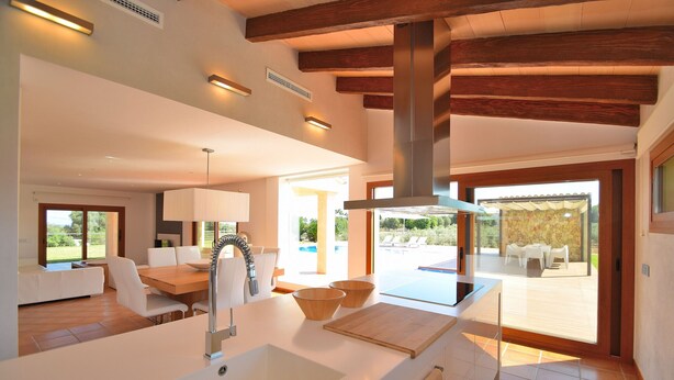 A modern kitchen with a large island, white cabinetry, and a view of an outdoor pool area.
