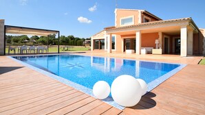 A modern house with a swimming pool, outdoor seating, and a covered patio.