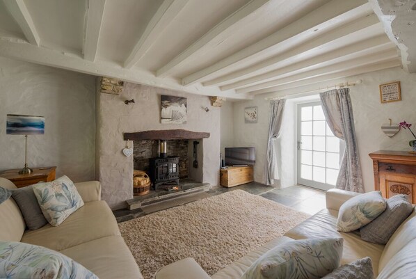 A cozy living room with a stone fireplace, a sofa, and a television.