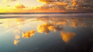 A calm beach with a reflective water surface and a clear sky with clouds. - Putsborough Manor Cottage (4 + Cot) Dogs Tennis Beach Jacuzzi Smart TV wifi (Croyde)