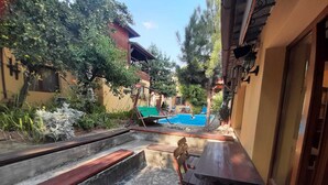 Une cour avec une piscine, un banc en bois et une table.