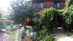 Une maison en bois avec un jardin, une piscine et un chemin en pierre.