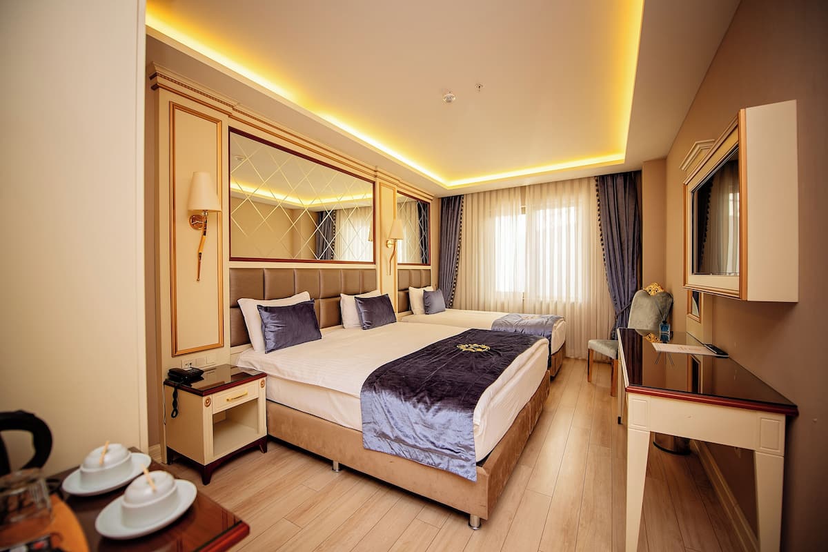 A hotel room with a large bed, bedside tables, a desk, and a mirror.