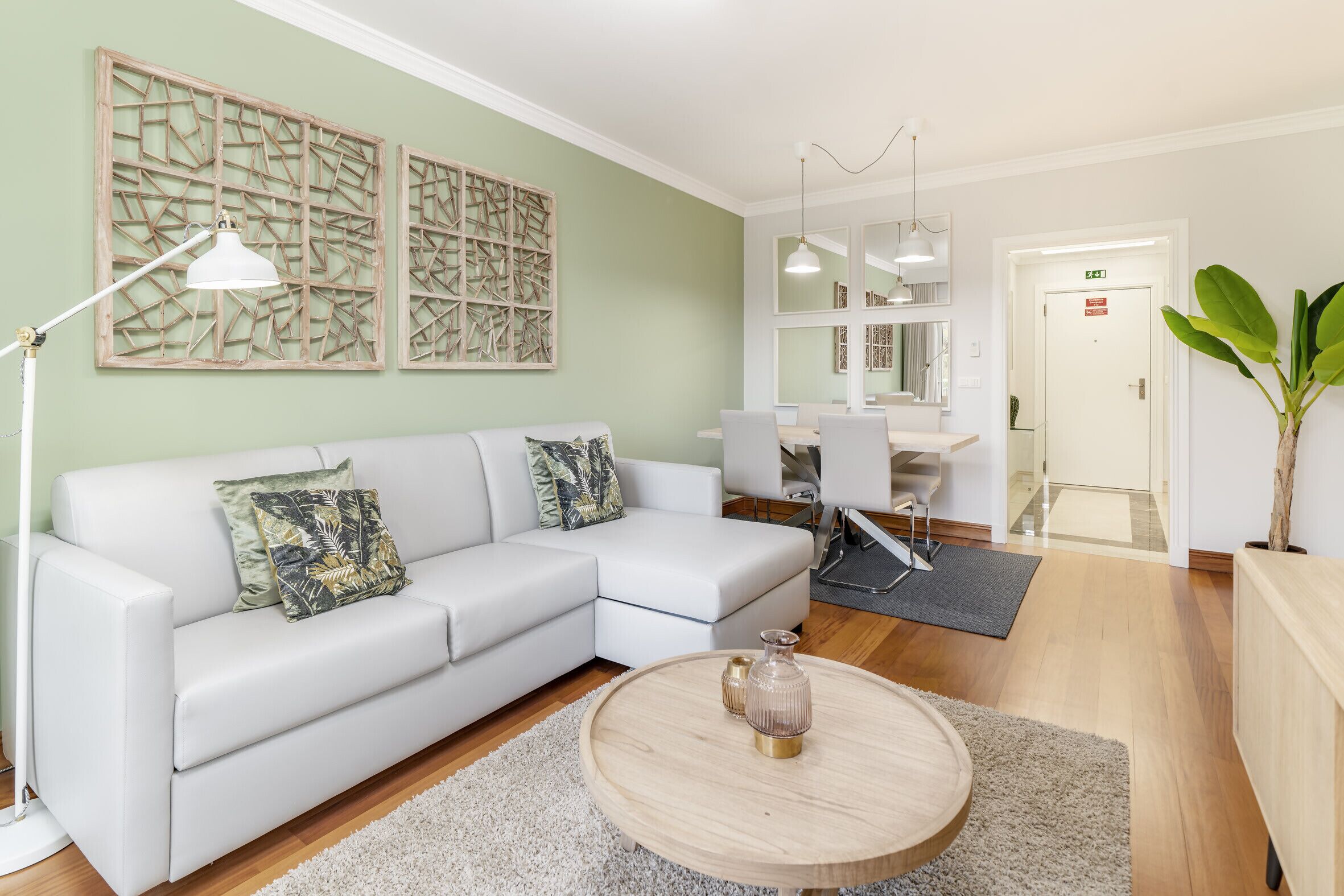 A modern living room with a white sofa, a round coffee table, and a dining area with a white table and chairs.
