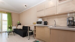 A modern kitchen with a microwave, coffee maker, and a dining area with a black sofa and a small table.