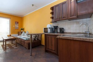 Uma cozinha compacta com armários de madeira, micro-ondas, máquina de café e pia.