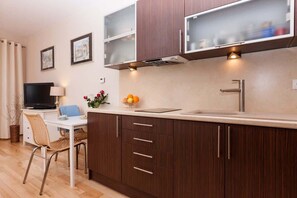 A modern kitchen with dark wood cabinets, a white countertop, a built-in microwave, and a stainless steel sink.