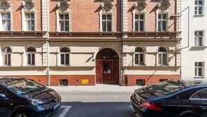 Un bâtiment doté d’une entrée centrale, de nombreuses fenêtres et de voitures garées dans la rue.