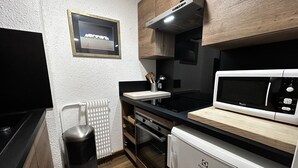 A compact kitchen with a microwave, stove, and dishwasher. - Ski-in/Ski-out Apartment for 6 in La Croisette with South-Facing Balcony (Les Menuires)