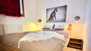 Un dormitorio con estructura de cama de madera, una manta blanca y un cuadro colgado en la pared de un zorro.