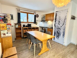 A compact kitchen with a dining table, chairs, and a refrigerator. - Stylish 2BR Apartment for 4-6 with Terrace, Ski-In/Ski-Out, Free Wifi (Valfréjus)