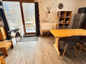 A cozy room with a wooden dining table, a sofa, and a view of a snowy outdoor area.
