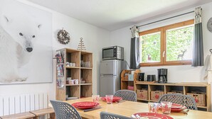 Un comedor con una mesa de madera, sillas negras y un refrigerador.