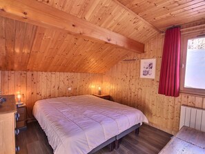 A wooden-paneled room with a bed, bedside tables, and a window with curtains.