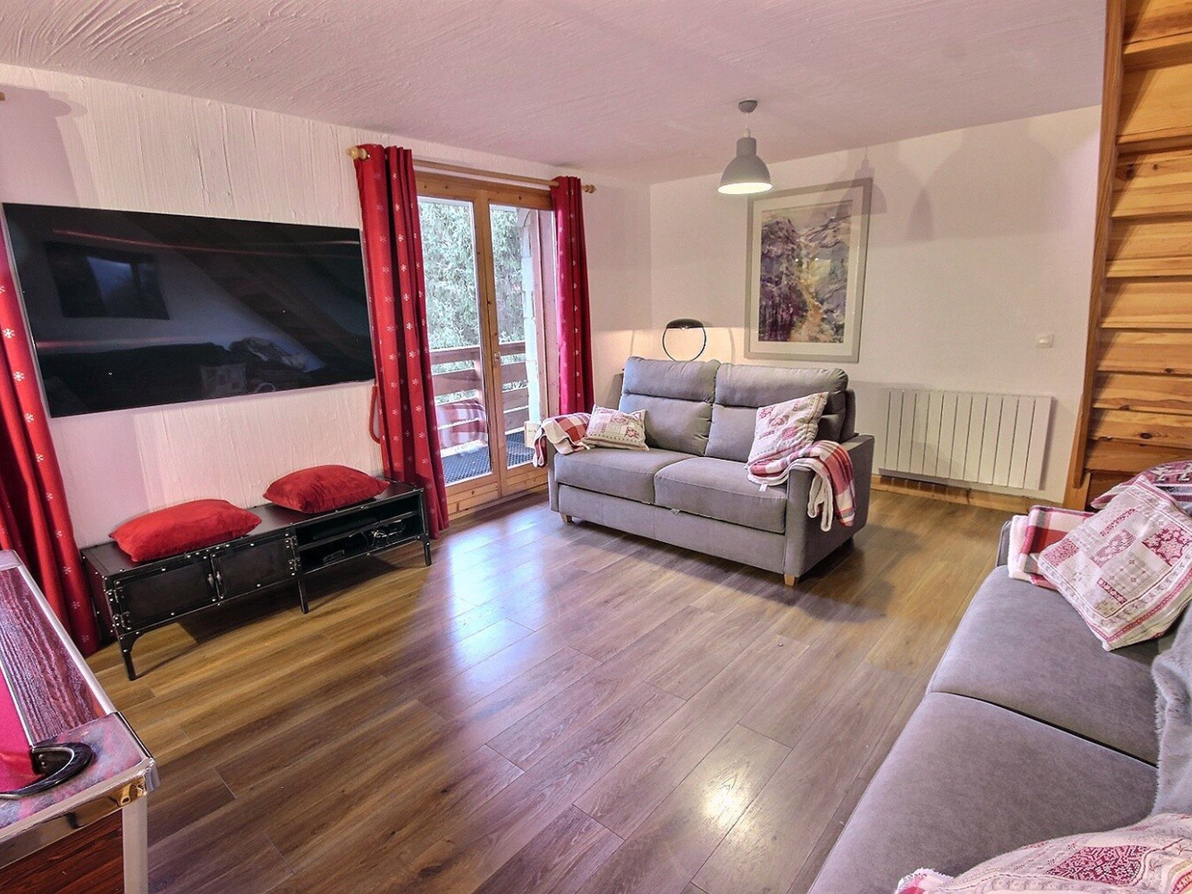 A cozy living room with a grey sofa, a black cabinet, and a red curtain.