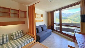 Una stanza con un divano, un letto a baldacchino, uno scaffale in legno e un'ampia finestra vista all'esterno.