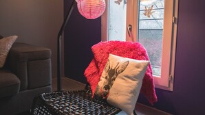 Ein Zimmer mit einem Korbsessel, einer Lampe und einer Tür, die nach draußen führt.